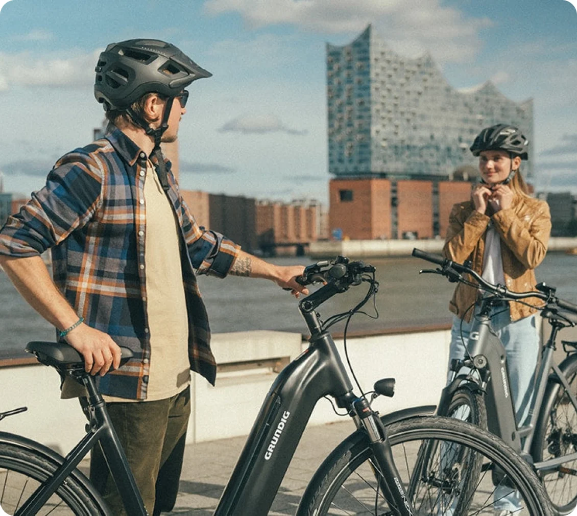 Two riders with Grundig e-bikes on a waterfront promenade